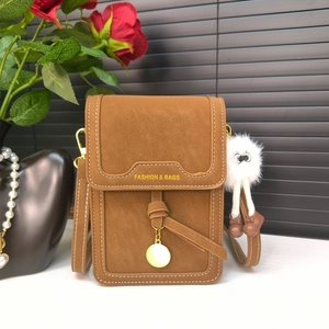 Close-up of brown crossbody phone bag with contrast stitching and plush keychain