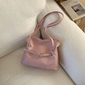 Close-up of pink pleated tote bag texture and silver buckle on a soft white sofa