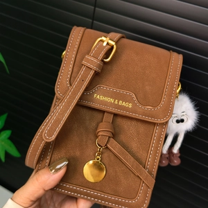 Detailed macro view of brown litchi pattern leather bag with white stitching and plush charm