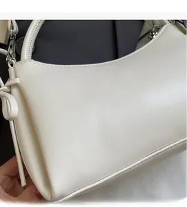 Primer plano del bolso de cuero crema que muestra la textura suave y la forma de media luna