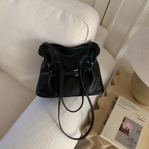Detail view of the black pleated leather tote bag with a decorative metal buckle strap