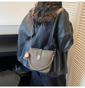 Détail du sac seau gris avec fermoir argenté et breloque petit cheval sur la bandoulière
