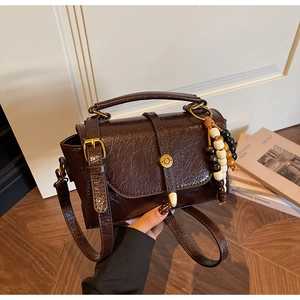 Detail of dark brown wrinkled PU leather mini square bag with vintage gold metal buckle