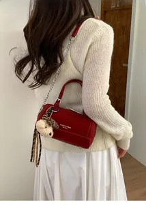 Détail du sac cylindrique rouge avec bandoulière en chaîne et charm ours en peluche