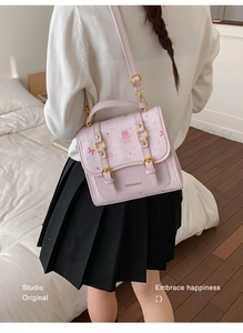 Detail of lavender textured crossbody bag with pink bow prints and adjustable shoulder strap