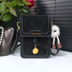 Close-up of black crossbody phone bag with contrast stitching and furry eye charm detail