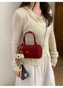 Détail du sac cylindrique rouge en cuir avec chaîne argentée et breloque ours