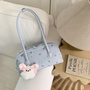 Close-up of light blue floral handbag with rabbit pendant on a cozy white sofa