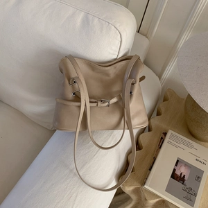 Detailed view of khaki pleated tote bag placed on a white sofa in a cozy home setting