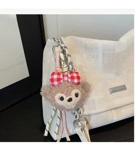 Dettaglio ciondolo orsetto di peluche con fiocco rosso su borsa a tracolla trapuntata