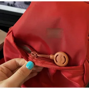 Dettaglio della cerniera in resina JingPin e trama in nylon rosso dello zaino casual
