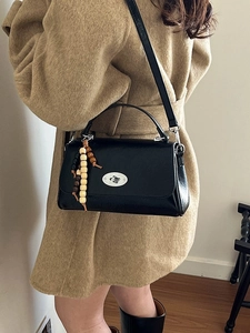 Classic black leather crossbody bag with silver oval twist lock and beaded charm
