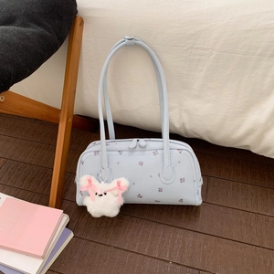Detail of light blue floral handbag with plush rabbit charm on indoor wooden floor