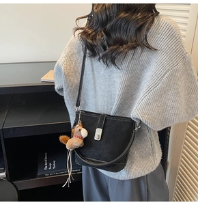 Détail du sac seau en cuir noir mat avec fermoir argenté et pendentif en forme de cheval