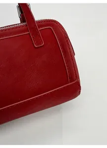 Détail du cuir rouge d'un sac à main avec coutures renforcées et finitions métalliques