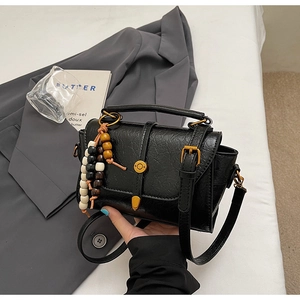 Detail view of black pleated leather bag with gold buckle and beaded charms