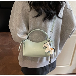 Detail of mint green crescent handbag with adjustable strap and cartoon horse charm