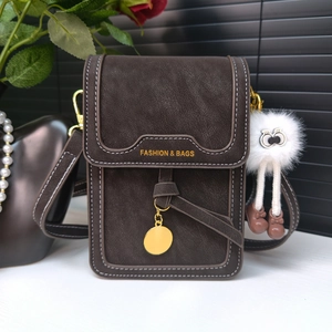Close-up of brown matte leather shoulder bag with white stitching and gold metal pendant