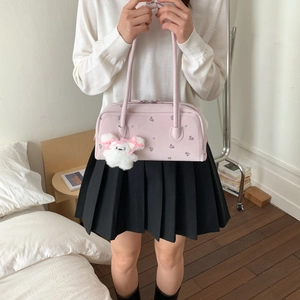 Detail of pink floral shoulder bag with plush charm shown in a cozy interior setting