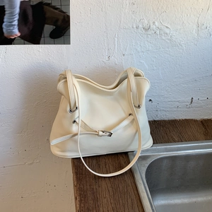 Detailed macro view of the cream leather texture and metal eyelets on the tote bag