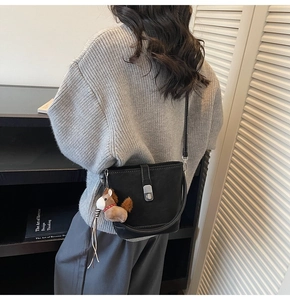 Détail du sac seau noir avec fermoir rotatif argenté et breloque en forme de cheval