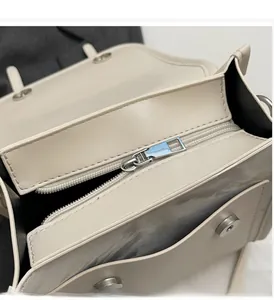 Close-up of beige leather bag showing light gold metal zipper and magnetic buckle detail