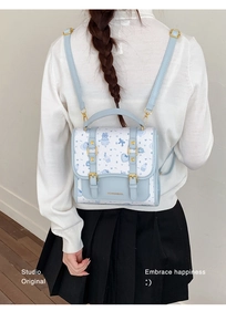 Close-up of a blue cartoon backpack with bears and hearts print and gold metal buckles