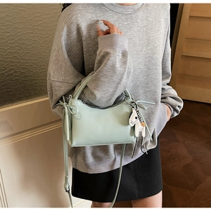 Detalle de bolso de mano minimalista verde menta en piel sintética con amuleto de caballo