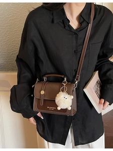 Retro dark brown leather crossbody bag with metal buckle and plush sheep charm on model