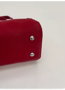 Détail macro de la base du sac à main en cuir rouge avec des clous de protection en argent