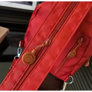 Vista macro di una borsa in nylon rosso con cerniera in metallo e logo JingPin