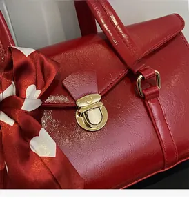 Gros plan détaillé d'un sac en cuir verni rouge avec boucle dorée et foulard en soie cœur