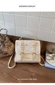 Close-up of cream-colored cartoon bear backpack with gold buckles on wooden table