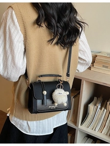 Classic black crossbody square bag with white stitching and gold lock on model