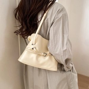 Detail view of a cream white pleated tote bag worn as a shoulder bag in minimalist style