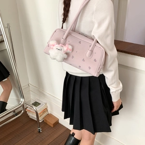 Pink floral shoulder bag with plush charm shown in a lifestyle model setting