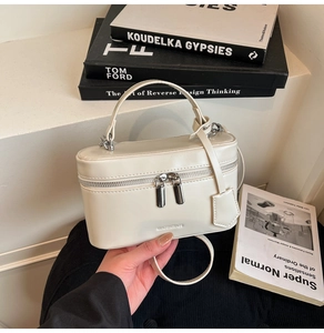 Macro shot of cream white mini box bag with gold double zipper and leather handle details