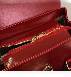 Vue détaillée de la fermeture éclair dorée et de la doublure sombre du sac à main rouge foncé