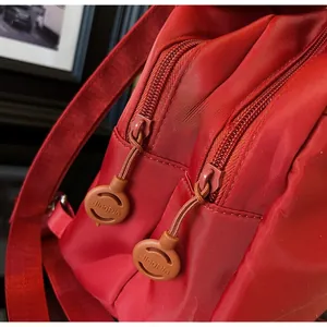 Dettaglio di uno zaino in tessuto oxford rosso con doppie cerniere scorrevoli