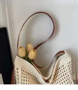 Detailed close-up of a woven hollow shoulder bag with long brown leather straps