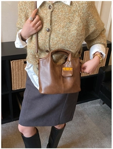 Détail d'un sac à main en cuir marron vintage avec un petit pendentif jaune décoratif