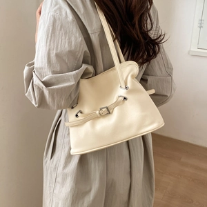 Detail of creamy white pleated shoulder bag featuring a metal buckle and adjustable strap