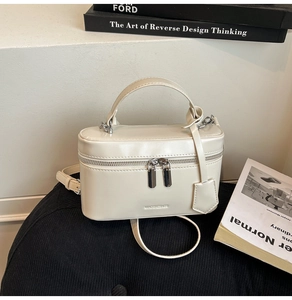 Close-up of cream PU leather vanity box bag with metallic zippers and top handle
