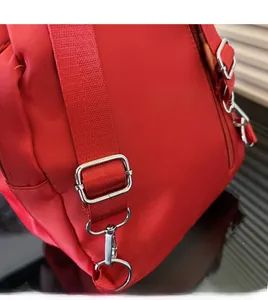 Dettaglio della tracolla regolabile in nylon rosso con ganci in metallo argento lucido