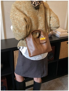 Détail du sac cabas en cuir marron avec boucle de cadenas dorée et doubles poignées