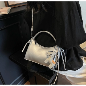 Bolso de mano plateado metalizado con forma de media luna y colgante decorativo
