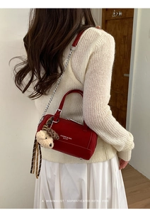 Détail du sac à main cylindrique en cuir rouge avec chaîne argentée et breloque ours