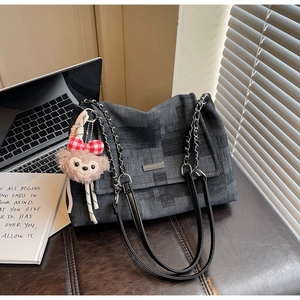 Dettaglio della borsa a tracolla in denim grigio scuro con logo argento e catena nera