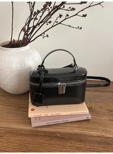 Detailed view of the black vanity case bag with silver hardware on a wooden table