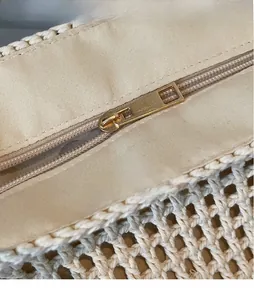 Close-up of golden zipper pull and woven cotton texture on beige tote bag
